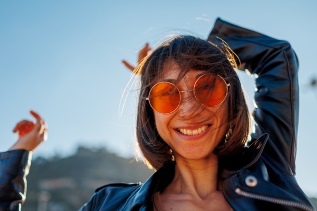 Girl dancing at a rock concert, stylish girl in a leather jacket dancing outdoors, rock music, happy woman in sunglasses.; Shutterstock ID 2591864863; purchase_order: -; job: NATURA COSMÉTICOS S.A.; client: -; other: